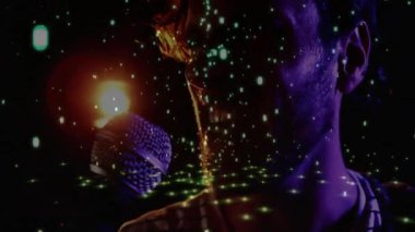 Erkek şarkıcı, mikrofon titreşimli spot ışıklarına yaslanıyor ve müzik performansı sırasında yeşil yıldızlar yanıp sönüyor. Konser, sanatçı, gece hayatı, sahne, aydınlanma, soyut, sanatsal