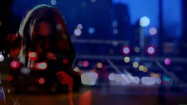 Siluet şarkıcısı öne çıkıyor, mikrofonu alıyor, şarkı söylüyor ve şehir ışıklarıyla kamerayı işaret ediyor. Konser, performans, gece hayatı, eğlence, sahne, performans, spot ışıkları