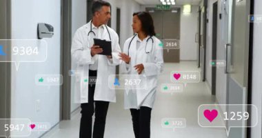 Klinik koridorunda yürüyen doktorlar tableti incelerken ve erişilebilir büyümeyi gösteren sosyal simgeler eklerken. İşbirliği, teknoloji, modern, sağlık, iletişim, yenilik, profesyonellik