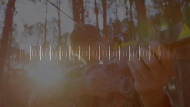 Çam ormanı güneş ışığı arasında yaylı tüfeği kaldıran adam avlanmak için alanı ayarlıyor. Avcılık, okçuluk, vahşi doğa, açık hava, hassasiyet, odaklanma, macera