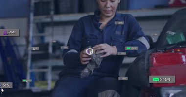 Tamirci araba garajında eldiven siliyor. Nişan kaldırma telefonunu gösteren ölçümlerin artmasına neden oluyor. Sanayi, otomotiv, atölye, teknoloji, üretkenlik, bakım, modern