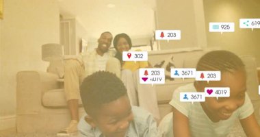 Çocuklar tableti tıklayarak sosyal medya simgelerini takip ediyor ebeveynler gözlemlerken. Aile, dijital eğlence, sosyal bağlantı, ev dekorasyonu, modern yaşam tarzı, çocuk aktivitesi, bağlanma anları