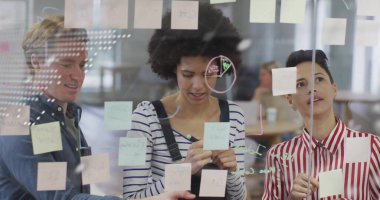 İşbirlikçi ekip ofisindeki cam duvara pastel yapışkan notlar yerleştiriyor. Kalem ve işaret diyagramlarıyla. İşbirliği, beyin fırtınası, planlama, takım çalışması, yenilik, modern, çalışma alanı