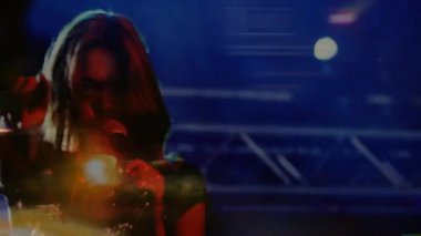 Sahne şarkıcısının üzerine ışıklar kayarken mikrofon tutarken ve müzik konserinde seyirciyi kendine çekerken. Performans, konser, aydınlanma, atmosfer, dinamik, seslendirme, eğlence