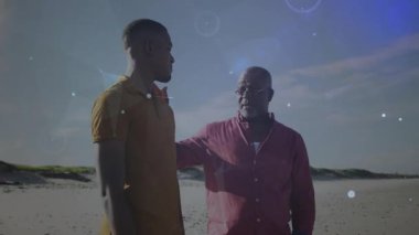 Baba, plajda oğlunun omzuna elini koyuyor, bağlantıyı sembolize eden teknoloji düğümlerini başlatıyor. Aile, akıl hocalığı, rehberlik, yetki, bağlantı, dijital, teknoloji