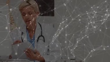 Doktor çizelge açıyor, notlar yazıyor ve muayene odasında teşhis için omurga modelini kontrol ediyor. Tıbbi, profesyonel, klinik, sağlık hizmetleri, belgeler, içgörü, çalışma alanı