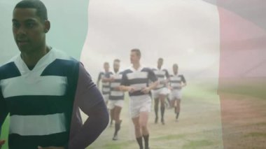 Soldan kareye koşan rugby takımı, ısınmak için İtalyan bayrağı altında puslu sahada volta atıyor. Sporcular, takım çalışması, atletizm, açık hava, spor, yoldaşlık, dinamik