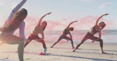 Yoga grubuna rehberlik eden kadın eğitmen kumsalda ters savaşçı kıvrımına giriyor, duman lambalarıyla. Egzersiz, sağlık, farkındalık, açık hava, doğa, uyum, dinginlik.