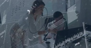 Meslektaş denetleme monitörü ayakta ve hareketli grafikleri oturarak iş verilerini doğrulayan olarak gösteriyor. İşbirliği, takım çalışması, analitik, modern, profesyonel, üretkenlik, iletişim