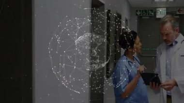 Doktor ağın hologramına bakarken hemşire koridora giriyor ve hasta verilerini tabletten inceliyor. Sağlık, işbirliği, dijital sağlık, teletıp, modern hastane, tıbbi teknoloji, klinik