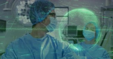 Cerrahlar cerrahi planlama için dinamik EKG grafiklerine dönüşen verileri üst üste koyarken birbirlerine bakıyorlar. Tıbbi, işbirliği, geleceksel, teknoloji, yenilik, kesinlik, profesyonellik