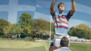 Rugby oyuncuları defansta koşuyor. Atlayıcıyı kaldırıyor, topu yakalıyor ve Yunan bayrağı soluyor. Atletik, takım çalışması, rekabet, açık hava, spor, çeviklik, dayanıklılık