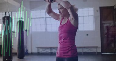 Kettlebell 'i kavrayan bayan sporcu, hareketli ölçümlerle fitness takibi için salıncaklar yapıyor. Güç, zindelik, eğitim, egzersiz, dijital, performans, sağlık