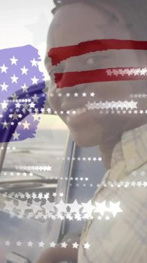 Amerikan bayrağının ve yıldızların animasyonu güneşli plajda arabasıyla mutlu bir Afrikalı Amerikalı adama karşı. Tatiller, yolculuklar, amerikan, vatanseverlik, kutlama ve gelenek, dijital olarak üretilen video.