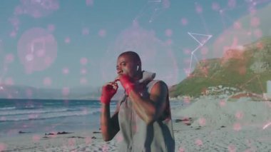 Kırmızı ambalajları sıkıyor kulaklık takıyor, boksör, antrenman için plajda pembe simgelerle yumruk atıyor. Sporcu, fitness, kararlılık, açık hava, yaşam tarzı, enerjik, dinamik