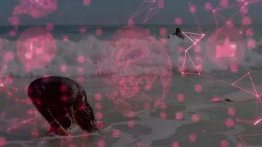 Dişi sörfçü, kafasını daldırdıktan sonra saçlarını savuruyor ve kumsalda holografik teknik grafikleri vurguluyor. Sörf, okyanus, dalgalar, plaj, spor, teknoloji, fütürizm