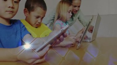 Eğitmen dizüstü bilgisayarları yerleştiren çocuklar tabletleri kaldırıyor ve ekranları canlandırılmış öğrenme simgeleriyle tıklatıyor. Eğitim, teknoloji, öğrenme, dijital, sınıf, takım çalışması, yenilik