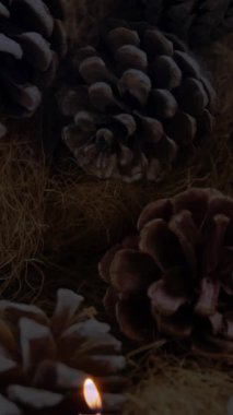 Arka planda çam kozalakları olan mum ve noel süslerinin animasyonu. Noel mevsimleri şenlik kutlaması konsepti dijital olarak oluşturuldu