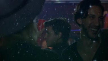 Arkadaşının kırmızı bardağı kaldırması, kameraya doğru gülmesi kutlama partisini canlandıran yıldız parıltılarını tetikliyor. Kutlama, sosyalleşme, gece hayatı, gündelik, sıcak, enerjik, arkadaşlık