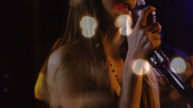 Baş vokalist mikrofonu kavrıyor Bokeh kaplamaları altında şarkı söylemeye başlıyor ve canlı müzik düetini ateşliyor. Performans, düet, konser, sahne, müzisyenler, canlı, duygusal