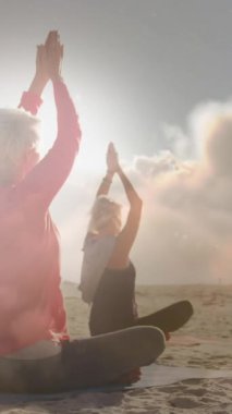 Deniz kenarında yoga yapan mutlu yaşlı kadınların üzerinde parlayan ışığın animasyonu. emeklilik ve yaşlı yaşam konsepti dijital olarak oluşturulmuş video.