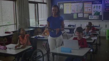 Öğretmen tableti tıklatıyor, sınıfta sıraların arasında yürüyor, dijital çizgiler kesişiyor. Eğitim, sınıf, teknoloji, öğrenme, öğrenciler, pedagoji, dijital