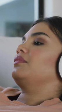 Altın ev anahtarı ve anahtarlığın evdeki kulaklık kullanan kadın üzerindeki animasyonu. Ev, ev, mülk, mülkiyet ve dijital olarak üretilen yaşam tarzı konsepti.