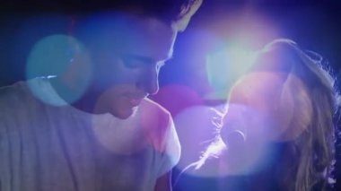 Kadın ve erkek müzik sahnesine ellerinde mikrofonla giriyor ve renkli spot ışıkları altında düet yapıyorlar. Performans, düet, sahne, konser, vokal, ahenk, spot ışığı