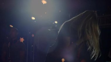 Sahne ışıkları, mikrofona eğilip kayan yıldız konfetiyle müzik yapan kadın şarkıcıyı işaret ediyor. Performans, sahne, kutlama, cazibe, eğlence, konser, sanatçılık