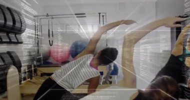 Pilates grubu, yenilikçilere, bar ayarlayan eğitmenlere ve kameraya yan esneme hareketleri yapıyor. Spor, sağlık, grup egzersizi, güç, esneklik, stüdyo, sakinlik.