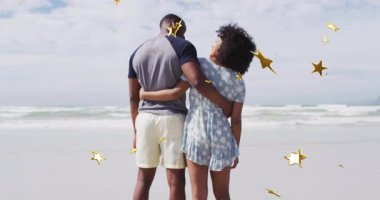 Kadın ve erkek kumsalda duruyor, altın konfeti romantik seyahat pazarlama anını başlatıyor. Romantizm, kutlama, deniz kenarı, dinginlik, şefkat, bağlantı, sükunet