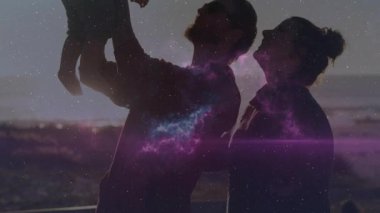 Erkek bebeği belden aşağı kaldırıyor, kadın izliyor, kozmik nebula altında aile bağı kuruyor. Siluet, göksel, duygusal, bağlantı, dinginlik, alacakaranlık, koruma