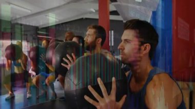 Eğitmen sinyaliyle, fitness sınıfı tıp toplarını kaldırıyor, çömeliyor ve topları hedefe fırlatıyor. Devre, takım çalışması, güç, eğitim, enerji, motivasyon, kardiyo