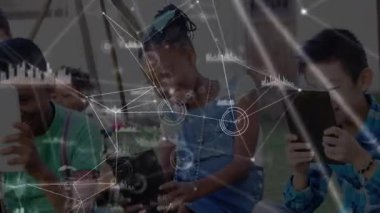 Çocuklar oyun bahçesindeki tabletlere tıklayarak eğitim için animasyon veri tablolarını aktifleştiriyorlar. Teknoloji, yenilik, eğitim, işbirliği, açık hava, gençlik, dijital