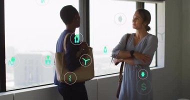 Enerji simgeleri oluşup etraflarında sürüklenirken iki bayan meslektaşı ofiste sohbet ediyor. Sürdürülebilirlik, işbirliği, kentsel, yenilikçi, profesyonellik, çevre dostu