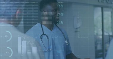 Orta yaşlı erkek doktor klinik koridorunda veri tartışması yapıyor, dijital çizelgeler etrafta dolaşıyor. Sağlık, teknoloji, analitik, işbirliği, yenilik, profesyonel, gelecekçi