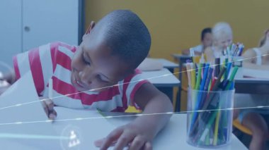 Çocuk sınıfta yazarken sayfayı çeviriyor ve öğrenme için avatarları birbirine bağlayan ağ simgelerini başlatıyor. Öğrenciler, eğitim, dijital, işbirliği, yenilik, anaokulu, öğrenim