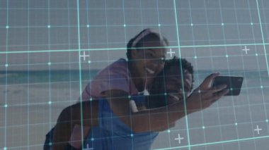 Kumsalda şebeke kaplamalı yürüyen bir çift, telefon kolunu uzatan bir kadın teknoloji selfie 'si çekiyor. Romantizm, bağlantı, açık hava, eğlence, mutluluk, modern, yaşam tarzı