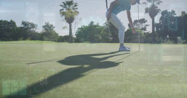Bayrak direğini tutan golfçü spor giyim ve fotokopi alanına yeşili koyarak golf topunu kapıyor. Atletik, boş zaman, açık hava, manzara, fitness, rahatlama, canlılık