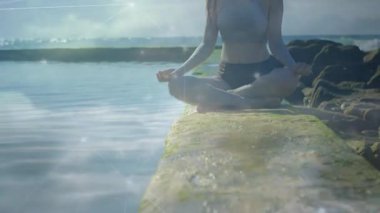 İskeleden yukarı doğru çekilen kamera, kadının Lotus 'ta meditasyon yaptığını ve iyileşme örtüsü oluşturduğunu gösteriyor. Dinginlik, farkındalık, doğa, açık hava, manzara, sükunet, maneviyat