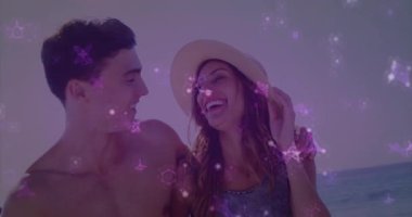 Erkek, plajda mor kıvılcımlar saçarak seyahat etmek için hasır şapkasını eğerek kadının kollarını sarıyor. Romantizm, rahatlama, tatil, uyum, eğlence, mutluluk, deniz kenarı.