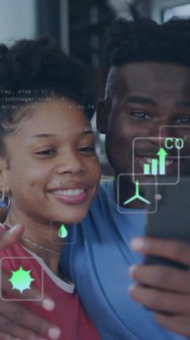 Akıllı opne kullanan mutlu Afro-Amerikan çifti üzerinden ekolojik simgelerin ve veri işlemenin animasyonu. Küresel yeşil enerji, bağlantılar, hesaplama ve veri işleme kavramı dijital olarak oluşturulmuş video.