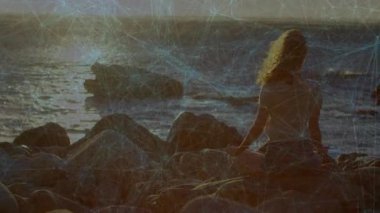 Kadın kayaları kaldırmaya başlıyor ve denize bakan derin meditasyona yerleşiyor. Dinginlik, tefekkür, doğa, sükunet, açık hava, farkındalık, rahatlama.