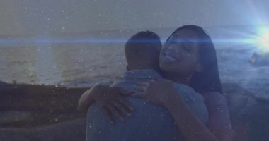 Kayalık sahil alacakaranlıklarında erkeğin kollarına sarılmış bir kadın, ışıldayan alevlerle sevgisini gösteren bir seyahat. Romantizm, samimiyet, sahil şeridi, dinginlik, bağlantı, alacakaranlık, düş gibi