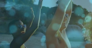 Arkadaşlar güneşli sahilde kollarını kaldırıp seyahat reklamları için bokeh efektli çizim grubu dansı yapıyorlar. Tan çizgileri, boş zaman, açık hava, yoldaşlık, hayat dolu, kaygısız, macera