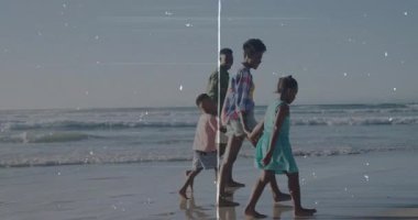 Çerçeveye sağ kenardan giriliyor, aile el ele tutuşuyor, seyahat için ıslak kumda geziniyor. Sahil, sahil, aile, bağ, sükunet, yansıma, açık hava.