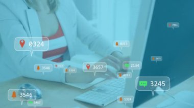 Ofisteki kadın klavyede yazmaya ve yükselen teknik uyarı simgelerini takip etmeye başladı. Üretim, dijital, arayüz, çalışma alanı, modern, katılım, teknoloji