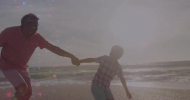 Okyanus dalgalarıyla yüzleşmek, kıdemli adamın çocuğun elini tutması ve çocuğun sağlık reklamı için hızlanması. Aile, deniz kenarı, siluet, bağ, açık hava, canlılık, rahatlık