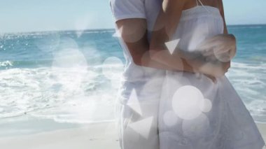 Kumsalda yürüyen çift, seyahat pazarında dalgalarla kollarını sarıyor. Romantizm, sonsuzluk, dinginlik, rahatlık, ufuk, samimiyet, uyum.