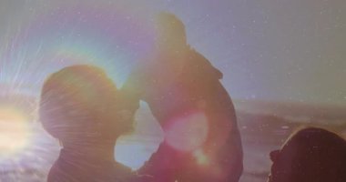 Baba, günbatımında mercek fişekleriyle sahilde bebek büyüterek ebeveynlik oyununu başlatıyor. Aileler, kaynaşma, yaşam tarzı, sıcak, hassas, açık hava, boş zaman